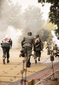 Soldado sanitario ayuda a herido durante una escena de guerra en una recreación histórica