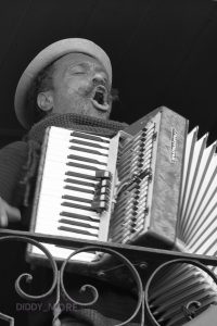 Retrato en blanco y negro de músico callejero tocando el acordeón en un balcón de Lisboa
