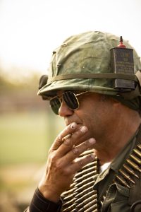 Militar con gafas y casco camuflado en pausa reflexiva durante recreación