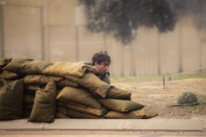 Joven agazapado tras sacos de arena durante una recreación histórica militar.