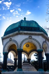 Fuente Alemana en Estambul con cúpula dorada y la Mezquita Azul al fondo en un cielo azul despejado.