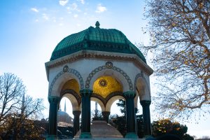 Fuente Alemana en la plaza de Sultanahmet, Estambul, con cúpula de cobre y mosaicos dorados al fondo de la Mezquita Azul