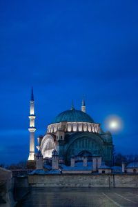 Mezquita iluminada de Estambul al anochecer con cielo azul intenso y luna llena