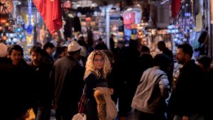 Mujer rubia con gafas en el Gran Bazar de Estambul rodeada de gente y luces de tiendas