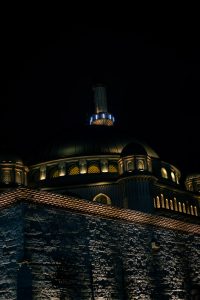 Cúpula de mezquita iluminada por la noche en Estambul, Turquía, con detalles arquitectónicos otomanos y cielo oscuro.