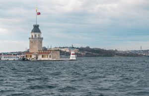 Torre de la Doncella de Estambul en medio del Bósforo con bandera turca y ferry atracado