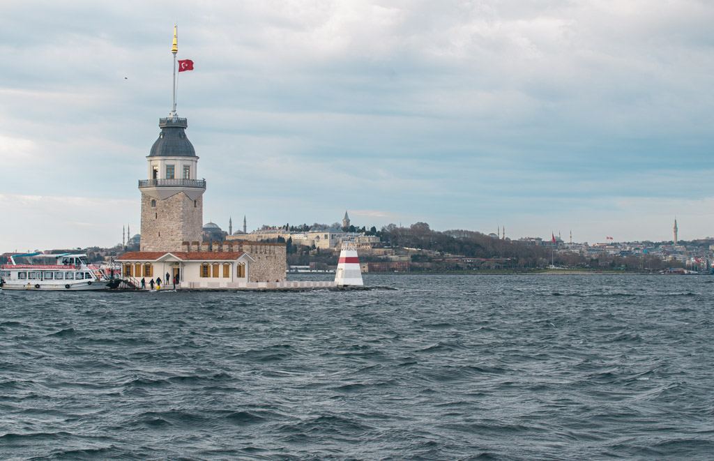 Torre de la Doncella de Estambul en medio del Bósforo con bandera turca y ferry atracado