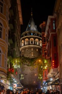 Vista nocturna de la Torre de Gálata iluminada, con ambiente animado en las calles de Estambul