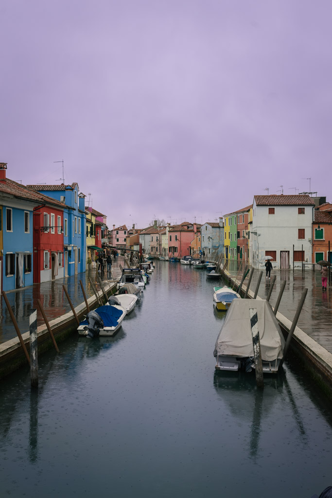 Barcas ancladas en un canal de Burano rodeado de casas de colores, en una excursión de Murano y Burano en un día.
