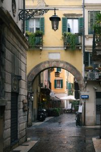 Calle tranquila y empedrada de Verona con edificios amarillos y arco de entrada. Verona desde Venecia en un día.