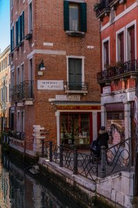 Fachadas de ladrillo y cartel de Sestiere di San Polo junto a pizzería en Venecia.