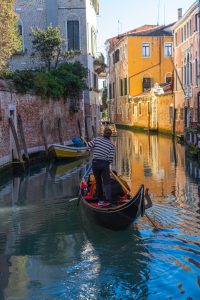 Góndola veneciana en un canal iluminado por el sol, una de las cosas que ver en Venecia en 1 día.
