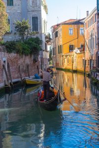 Góndola navegando un canal colorido en el centro de Venecia.