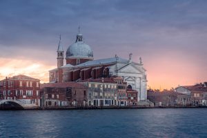 Iglesia del Redentor en Venecia al atardecer con cielo rosado y reflejos sobre el canal