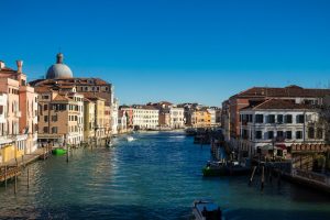 Vista del Gran Canal de Venecia con fachadas de colores y cielo azul en un día despejado
