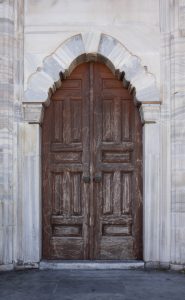 Puerta de madera antigua con marco de mármol tallado en una mezquita de Estambul, estilo otomano tradicional