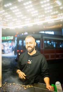 Vendedor ambulante de castañas en Estambul de noche, junto a un tranvía rojo típico.