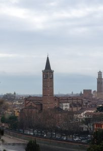 Vista de la iglesia de Santa Anastasia en Verona con su campanario gótico al atardecer, junto al río Adigio.