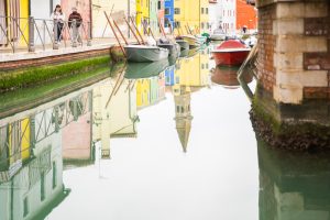 Reflejo nítido de casas de colores y el campanario en el canal de Burano, capturado durante una visita de Murano y Burano en un día.
